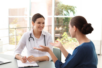 Wall Mural - Young doctor listening to patient's complaints in hospital