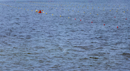 Wall Mural - background. orange canoe with two oarsmen in life jackets, floating on the river, the sea, the ocean.