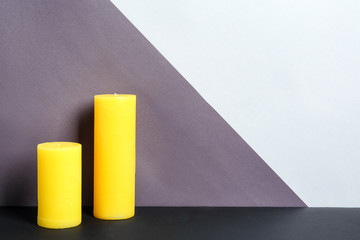 Decorative wax candles on table against color background