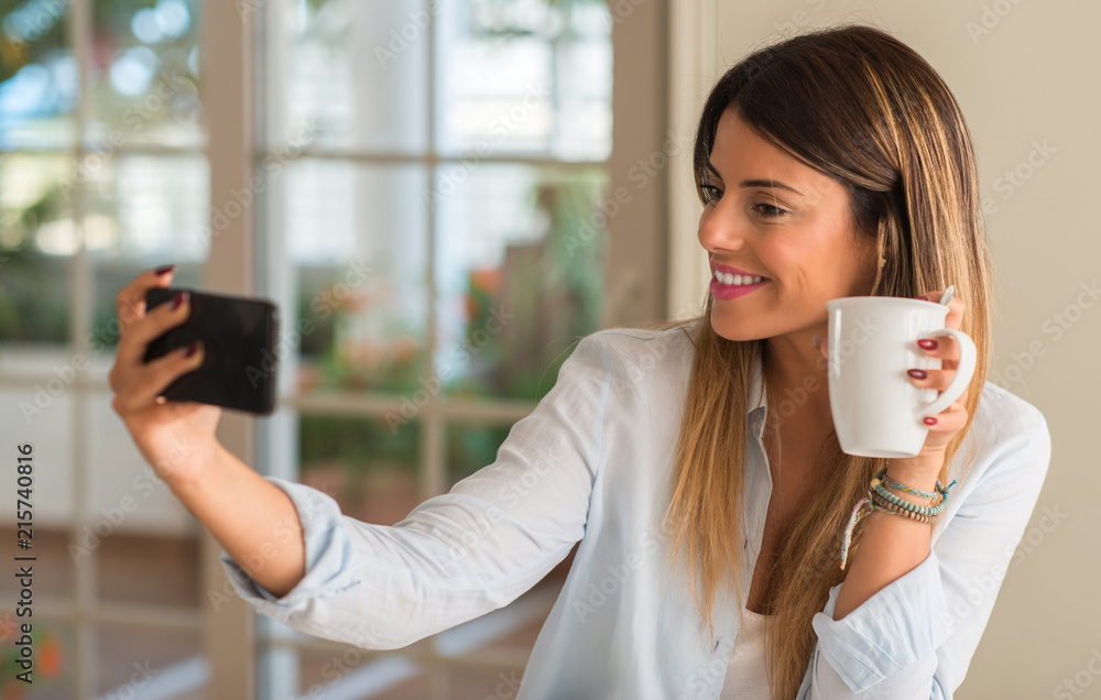 Beautiful young woman taking a selfie with phone while drinking cup of ...