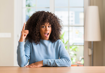 Poster - African american woman at home pointing finger up with successful idea. Exited and happy. Number one.