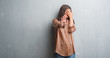 © Krakenimages.com - Young brunette woman over grunge grey wall covering eyes with hands and doing stop gesture with sad and fear expression. Embarrassed and negative concept.