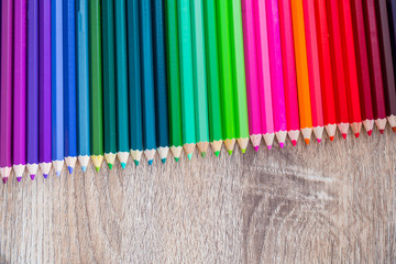 Multi Color pencils in scale with rainbow style isolated on wooden background