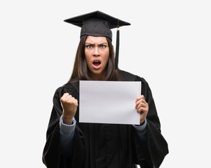 Sticker - Young hispanic woman wearing graduated uniform holding diploma paper annoyed and frustrated shouting with anger, crazy and yelling with raised hand, anger concept