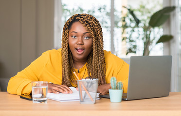 Canvas Print - African american woman studying with laptop scared in shock with a surprise face, afraid and excited with fear expression