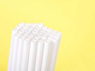 Dozens of biodegradable eco-friendly paper straws bundled together facing forward and upwards on a yellow background with copy space. Many cities are now banning single use plastic straws.