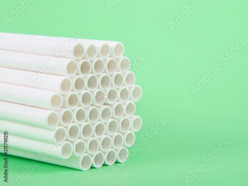 Fotografie, Obraz Dozens of biodegradable eco-friendly paper straws bundled together facing forward on a green background with copy space