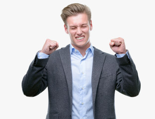 Poster - Young handsome blond business man excited for success with arms raised celebrating victory smiling. Winner concept.