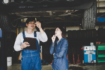 Wall Mural - Young mechanic with clipboard talking to woman or owner at car shop. explain repair service.