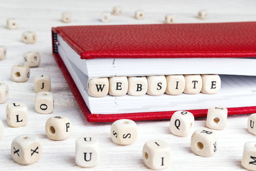 Word Website written in wooden blocks in red notebook on white wooden table.