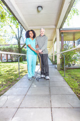 Poster - African nurse helping elderly man with crutch in rehab facility hallway