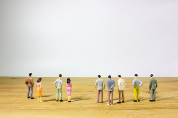 miniature business people on wooden table watching to white background.