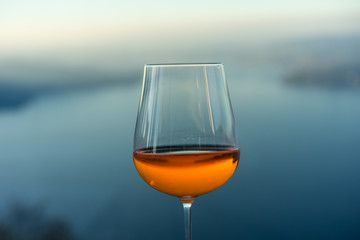 wine glass with drink in front of blue lake iconic background