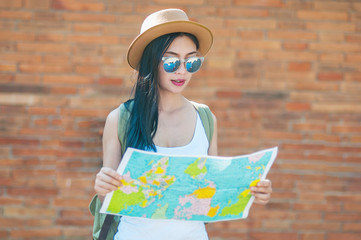 Tourist travel woman looking at the map while walking on a street  - street backpack travel concept