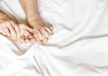 Couple Having Sex. Hand Clutches Grasps A White Crumpled Bed Sheet In A Hotel Room, A Sign Of Ecstasy, Feeling Of Pleasure Or Orgasm