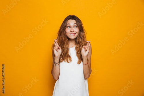 Fotomural Portrait of an excited young girl holding fingers crossed
