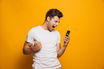 Poster - Portrait of a thrilled young man looking at mobile phone