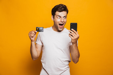 Wall Mural - Portrait of a cheerful young man holding mobile phone