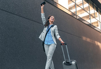 Wall Mural - Young woman on business trip walking with her luggage at airport.