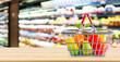 © Kwangmoozaa - Shopping basket with fruit on wood table over grocery store supermarket blur background