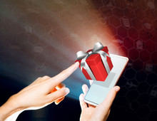 Hands Of A Woman Is Holding A Smartphone. She Clicks On The Gift. Concept Of Gift Giving, Choice Of Gifts.