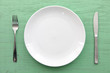 © jedi-master - 緑の木製テーブルに置かれた白い皿とカトラリー