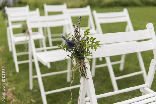 Fotografía White wedding chairs decorated with fresh flowers on a green grass