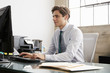 © Monkey Business - Young white businessman using a computer at an office desk