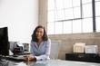 © Monkey Business - Young mixed race woman at office desk smiling to camera