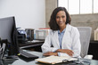© Monkey Business - Young female doctor sitting at desk in an office, portrait