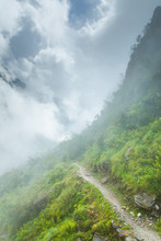 Mystic Trail Winding Through The Clouds Of A Lush Green Hillside In The Annapurna Himalaya, Nepal.