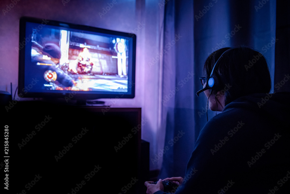 Young Male Gamer With Glasses And Headset Playing Video Game