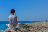 Fototapeta  - Dziewczyna siedząca na skale nad morzem, patrząca na wrak statku MV Demetrios II, Paphos, Cypr