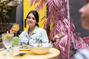 Wall Mural - Relaxing on terrace. Stylish dark-haired woman relaxing on decorated summer terrace with her best friend
