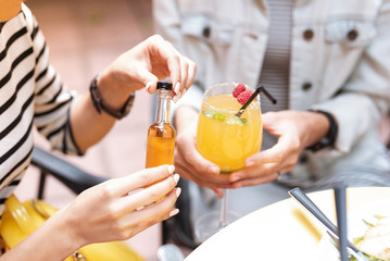 Wall Mural - Adding cognac. Woman with nice beige nail art adding some cognac to refreshing summer cocktail