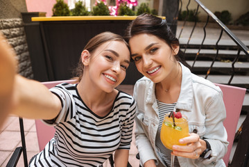 Wall Mural - Woman with phone. Dark-haired woman wearing striped shirt holding phone while making photo with her friend