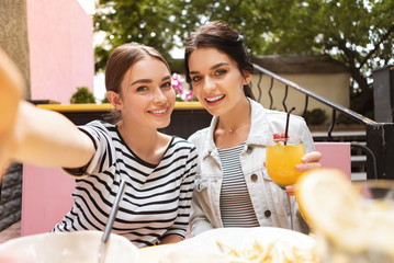 Wall Mural - Smiling woman. Smiling woman wearing jeans jacket drinking cocktail while posing for photo with her friend