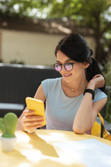 Wall Mural - Reading messages. Beaming businesswoman reading messages on her phone while spending break in restaurant