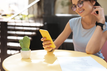 Wall Mural - Typing message. Smiling beautiful freelancer wearing black leather wrist watch typing message for her friend
