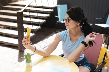 Wall Mural - Photo while waiting. Dark-haired stylish woman making selfie while waiting for her dessert and coffee
