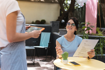 Wall Mural - Order in restaurant. Pleasant fashionable woman wearing nice blue shirt placing her order in restaurant