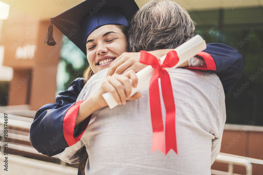 Graduated student hugging her father - obrazy, fototapety, plakaty 