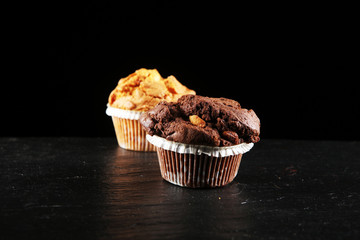 Chocolate muffin and nut muffin, homemade bakery on dark background.