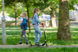 © madhourse - The girl is happily riding a scooter along an asphalt road