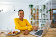 © Bonninstudio/Stocksy - Young woman eating snack whilst working at office.