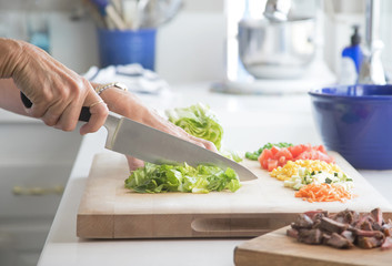 Photograph of a woman's hand cutting up vegetable for a salad