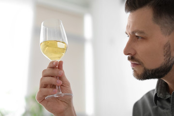 Man with glass of delicious wine indoors