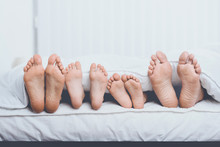 Close Up Family In Bed Under Cover Showing Feet