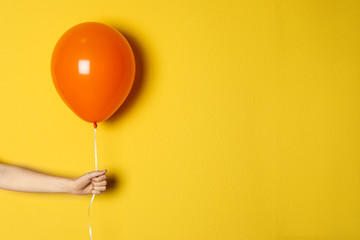 woman holding orange balloon on color background