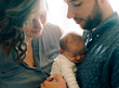 © Marta Locklear/Stocksy - Father and mother admiring their new baby boy with light filtering in.